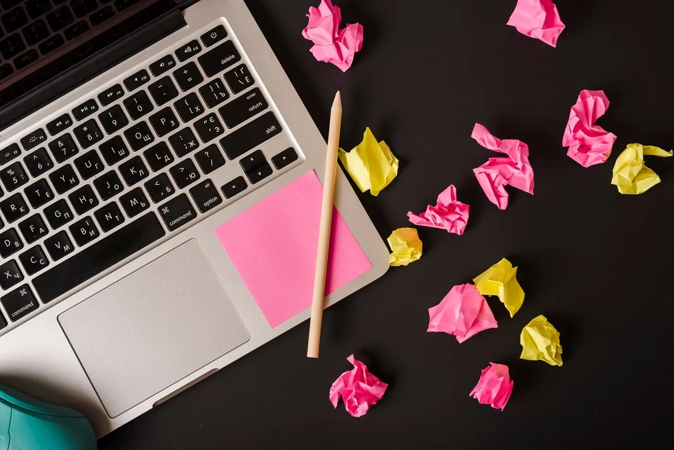 Eine Draufsicht auf einen Laptop mit Stift und Haftnotizen auf schwarzem Hintergrund.